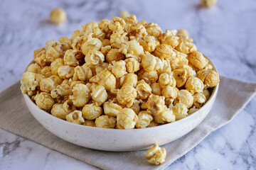 Bowl of caramel popcorn. Popular food for movie snacks. Selective focus with blurred foreground and background.