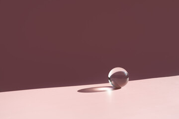 transparent ball on a pink background with hard shadows. minimalist composition.