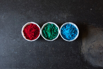 Concept of RGB colors or red, green and blue powder colors in bowls on a dark background.