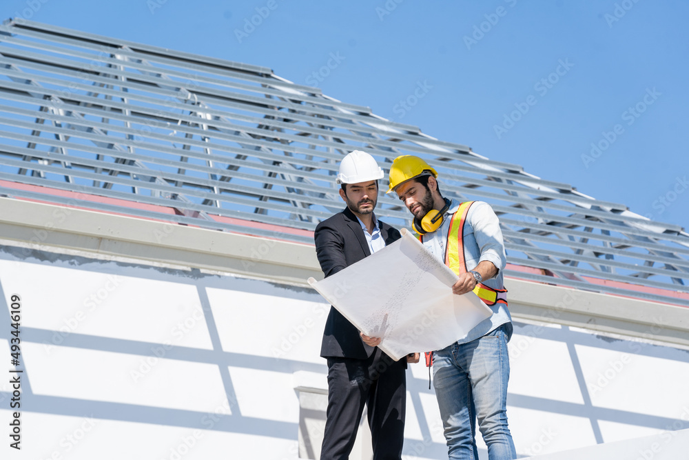 Poster engineers discussion with consultants about detail of building plans for new home at construction si