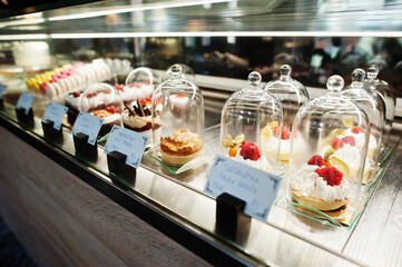 Tartlet desserts under the glass dome in shop window at cafe.
