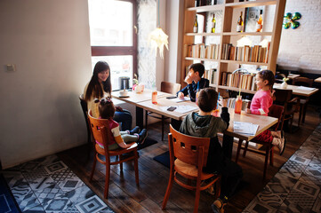 Mother with four kids spending time in cafe. Family lunch in the cafeteria.