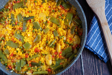 Rice paella with vegetables on a rustic background