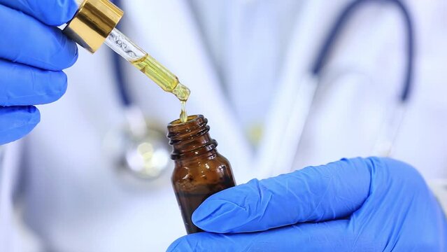 Doctor in blue gloves stands holding cannabis extract oil. for use in the treatment of cancer Blurred image background as a doctor wearing a stethoscope health care concept recreation for happiness.
