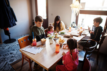 Mother with four kids spending time in cafe. Family lunch in the cafeteria.