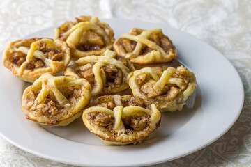 Little apple pies with cinnamon and dough decoration on a plate - apple tartlets close up with selective focus