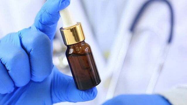 Doctor in blue gloves stands holding cannabis extract oil. for use in the treatment of cancer Blurred image background as a doctor wearing a stethoscope health care concept recreation for happiness.