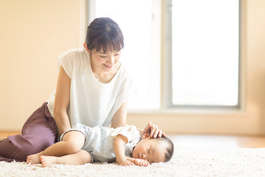 カーペットで眠る子供を見守る母親