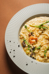 Appetizing risotto with seafood (shrimp and mussel) garnished with microgreens (pea sprouts) in a beautiful white plate.