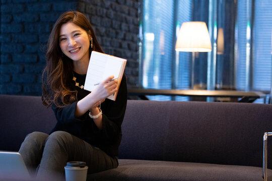 開いた手帳を見せる女性