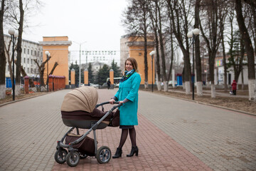 Young mother walking with baby carriage in park