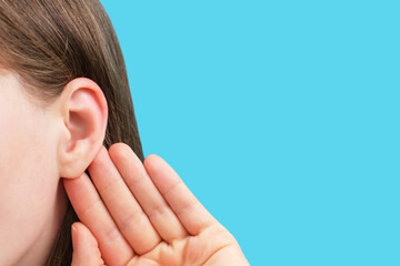 The girl listens attentively with her palm to her ear close up, news concept.