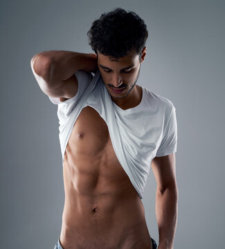 These abs were made for showing. Studio shot of a handsome young man posing against a grey background.