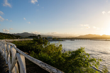 Obraz premium Sunset at Puerto Plata. Beautiful sky at sunset over green hill and rural white fence. Colorful and vibrant clouds. The soft light of the setting sun.