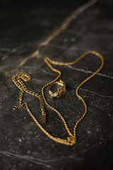 Gold ring in the shape of a crocodile with a gold chain on a dark marble background