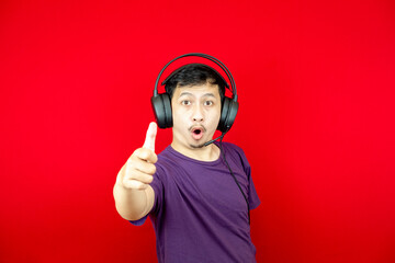Asian man wearing headset satisfied and happy showing thumbs up sign, agree symbol.
