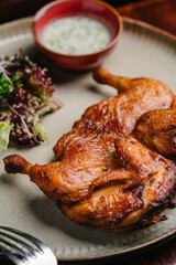 Grilled fried roast Chicken Tabaka with garlic sauce and salad on a wooden table