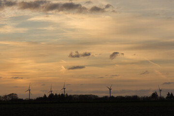 Fototapeta premium Windräder mit Himmel und Wolken beim Sonnenuntergang