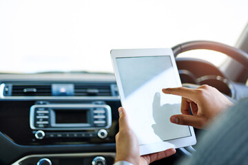 Preparing for work en route to work. Cropped shot of an unidentifiable man using a digital tablet while driving a car.