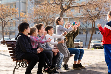 Fototapeta premium Group of kids relaxing on bench on playground, playing with ball true or false game