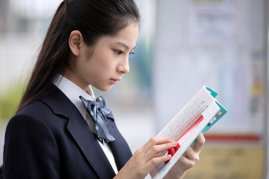 勉強しながらバスを待つ女子高校生