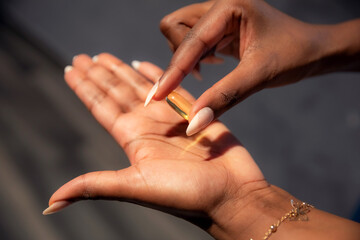 Obraz na płótnie Canvas Yellow gel oil capsule of pill (Omega or vitamin D3) in the hands of African ethnicity woman close up