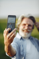 Old farmer in shirt standing on field with notebook