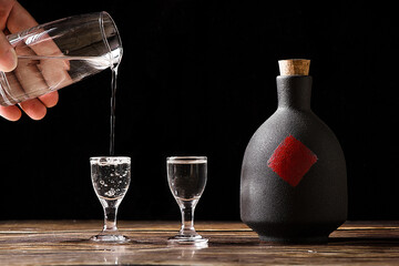 chinese liquor is poured into a glass from a bottle on wood background