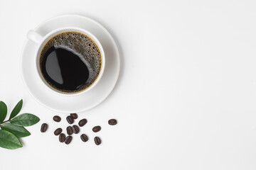 Black coffee in a cup and coffee beans with green leaves isolated on a white background.