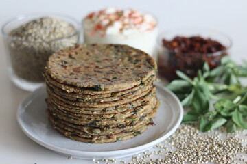 Bajra methi thepla. Indian flat bread made of pearl millet flour, fenugreek leaves, sesame seeds, yogurt and spices. Served with yogurt and spicy garlic condiments