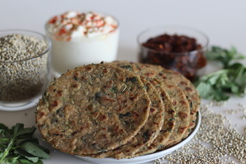 Bajra methi thepla. Indian flat bread made of pearl millet flour, fenugreek leaves, sesame seeds, yogurt and spices. Served with yogurt and spicy garlic condiments