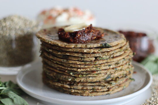 Bajra methi thepla. Indian flat bread made of pearl millet flour, fenugreek leaves, sesame seeds, yogurt and spices. Served with yogurt and spicy garlic condiments