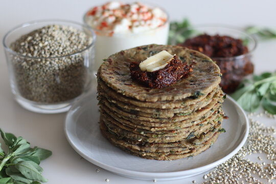 Bajra methi thepla. Indian flat bread made of pearl millet flour, fenugreek leaves, sesame seeds, yogurt and spices. Served with yogurt and spicy garlic condiments