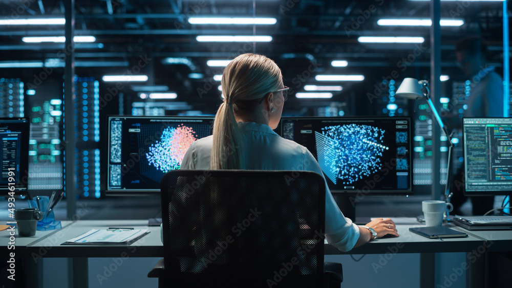 Fototapete Futuristic Concept: Female Computer Engineer Looking on the Two Displays while Working on the Computer. Screen Shows Interactive Neural Network, Artificial Intelligence Project, User Interface