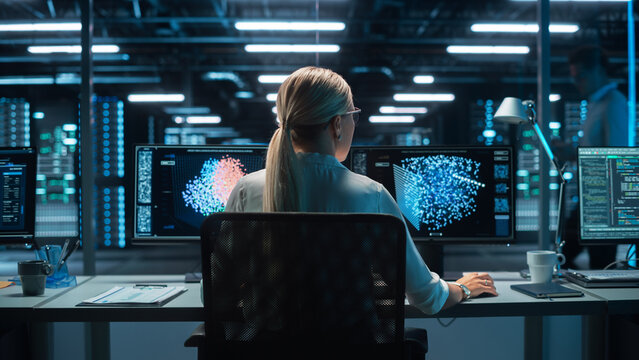 Futuristic Concept: Female Computer Engineer Looking on the Two Displays while Working on the Computer. Screen Shows Interactive Neural Network, Artificial Intelligence Project, User Interface