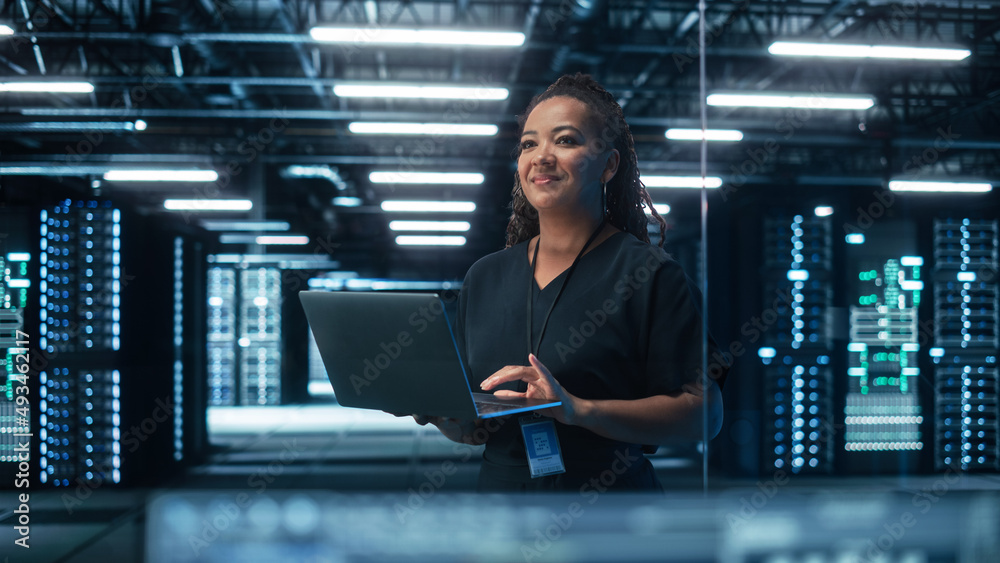 Fototapete Portrait of Multiracial Mature Female IT Specialist Using Laptop, Standing in Data Center. Infrastructure Architect Works on Web Services. Cloud Computing, Server Analytics, Cyber Security Maintenance