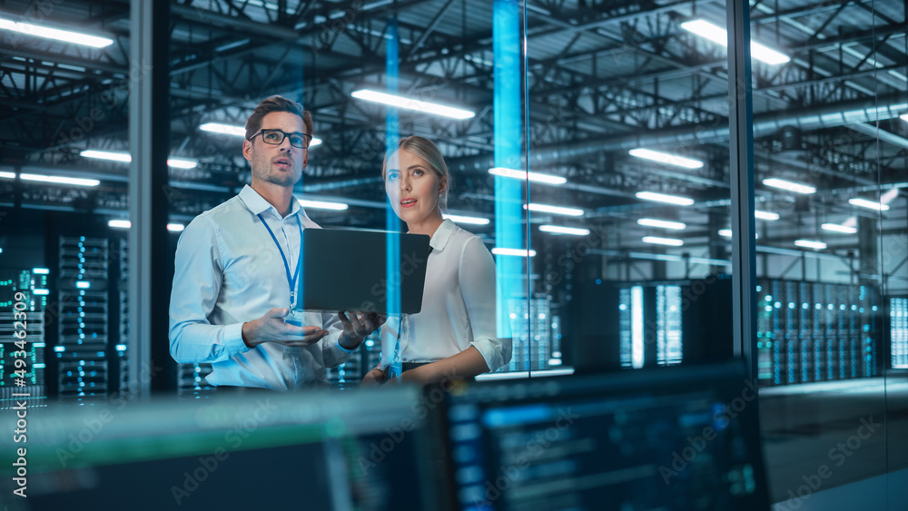 Poster in data center: male and female business partners talk, look away and brainstorming at the evening o