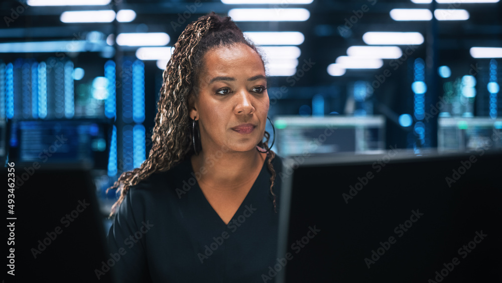 Fototapete Focused IT Specialist Working on Computer in Office Environment. Diverse Multiethnic Female Developer is Using Two Monitors while Writing Code Late at the Night