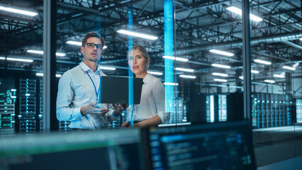 In Data Center: Male and Female Business Partners Talk, Look Away and Brainstorming at the Evening...