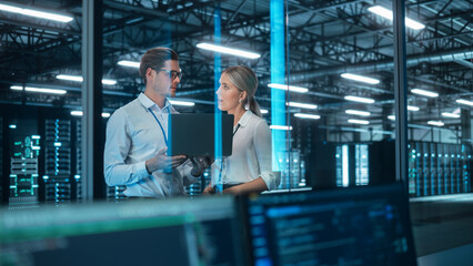 Male and Female Server Engineers Work on a Laptop in Data Center. They Look Away and Think About...