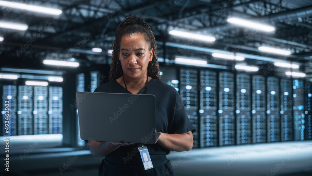 Poster Mixed Race IT Specialist Using Tablet Computer in Data Center, Looking Attentively at the Screen and Working with Big Server Farm Cloud Computing Facility. Businesswoman, e-Business Entrepreneur