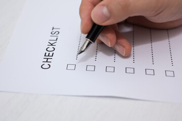 Close-up Of Person's Hand Marking On Checklist Form