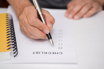 Close-up Of Person's Hand Marking On Checklist Form