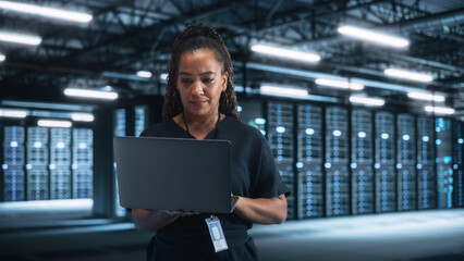 Mixed Race IT Specialist Using Tablet Computer in Data Center, Looking Attentively at the Screen...