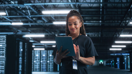 Female Engineer Programs while Holding Tablet Computer and Typing at the Screen. She Works in a Dark Modern High-Tech Office. High-Speed Data Transfer and Smooth Server Operation Concept