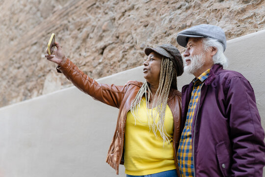 happy multiracial elderly couple take pictures and travel around the city - retirement travel -