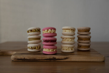 Colored sweet almond cookies, multicolored with cream, composition on a wooden table.