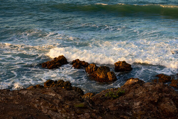 Rocky coast and waves washing over the stones near the beach. Sunset in the Dominican Republic. Caribbean background.