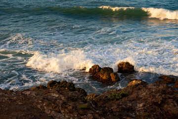 Rocky coast and waves washing over the stones near the beach. Sunset in the Dominican Republic. Caribbean background.