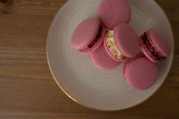 Pink sweet almond cookies with cream, a composition on a wooden table.